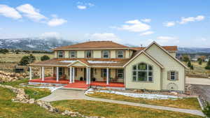 View of front facade with covered porch, a mountain view, and a front lawn