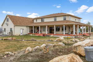 Back of property with a lawn and covered porch