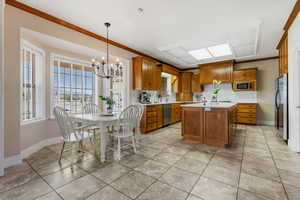 Kitchen with a center island, stainless steel appliances, an inviting chandelier, decorative light fixtures, and ornamental molding