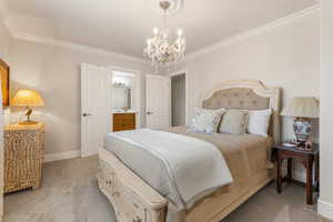 Carpeted bedroom featuring crown molding and a notable chandelier