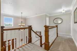 Stairs with carpet flooring, crown molding, and an inviting chandelier