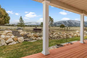 Wooden terrace featuring a mountain view and a yard