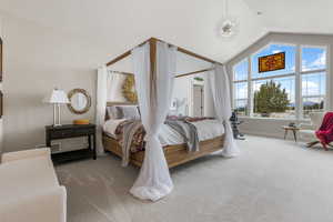 Carpeted bedroom with vaulted ceiling and an inviting chandelier