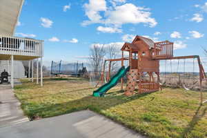 View of jungle gym featuring a yard, a trampoline, and a patio area