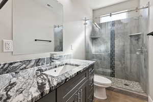 Bathroom with walk in shower, tile patterned floors, vanity, and toilet