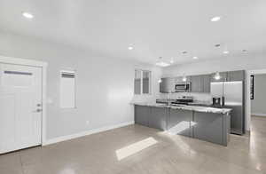 Kitchen with sink, stainless steel appliances, light stone counters, pendant lighting, and gray cabinets