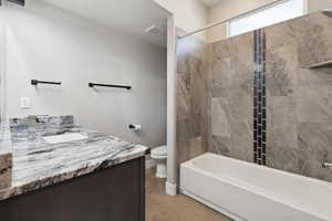 Full bathroom featuring tiled shower / bath, vanity, and toilet