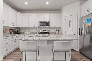 Kitchen with white cabinetry, an island with sink, and stainless steel appliances