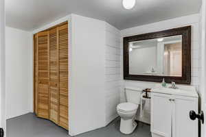 Bathroom with vanity, concrete flooring, a textured ceiling, and toilet