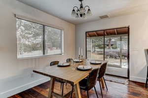 Dining room with dark wood-type flooring, a textured ceiling, and a notable chandelier