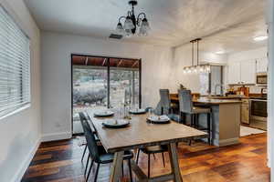 Dining area featuring dark wood-type flooring, a textured ceiling, and an inviting chandelier