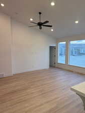 Spare room with ceiling fan, lofted ceiling, and light wood-type flooring