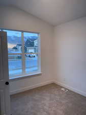 Unfurnished room featuring carpet flooring and lofted ceiling