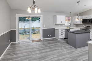 Kitchen featuring a center island, an inviting chandelier, sink, appliances with stainless steel finishes, and white cabinetry