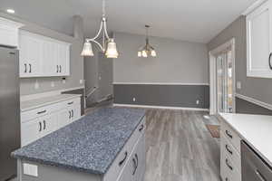 Kitchen featuring stainless steel appliances, a kitchen island, light hardwood / wood-style floors, pendant lighting, and white cabinets