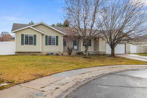 Ranch-style house featuring a garage and a front lawn