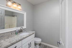 Bathroom featuring wood-type flooring, vanity, toilet, and walk in shower