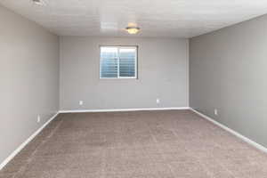 Carpeted spare room featuring a textured ceiling