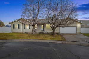 Ranch-style home featuring a garage and a lawn