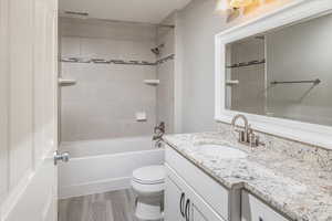 Full bathroom featuring hardwood / wood-style floors, vanity, toilet, and tiled shower / bath combo