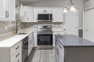 Kitchen featuring appliances with stainless steel finishes, white cabinetry, pendant lighting, and sink