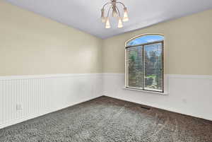 Carpeted spare room with a notable chandelier