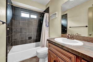 Full bathroom with vanity, tile patterned flooring, decorative backsplash, toilet, and shower / bathtub combination with curtain