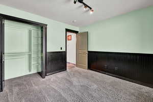 Unfurnished bedroom featuring carpet floors, a closet, and rail lighting