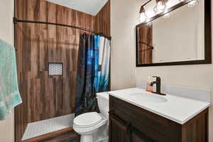 Bathroom featuring walk in shower, vanity, and toilet