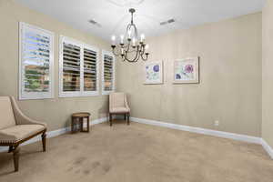 Sitting room featuring a notable chandelier, light colored carpet, and plenty of natural light