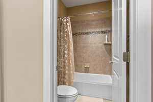 Bathroom with shower / bath combination with curtain and toilet