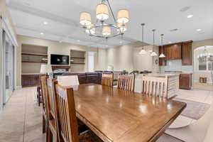 Dining room featuring a fireplace, beam ceiling, light tile patterned floors, and a notable chandelier