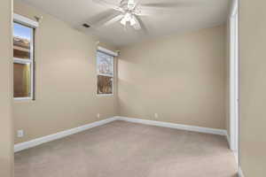 Spare room with ceiling fan, light colored carpet, and plenty of natural light