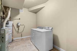 Laundry room featuring secured water heater, independent washer and dryer, and a textured ceiling