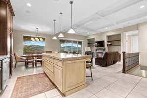 Kitchen with a breakfast bar, built in shelves, light tile patterned floors, a kitchen island, and hanging light fixtures