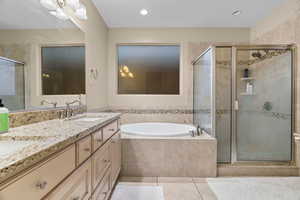 Bathroom featuring shower with separate bathtub, vanity, and tile patterned floors