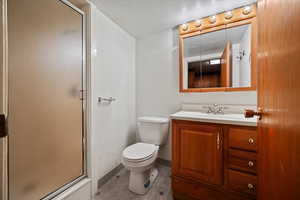 Bathroom featuring vanity, toilet, a shower with door, and a textured ceiling