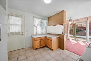 Kitchen with kitchen peninsula, light carpet, and ceiling fan