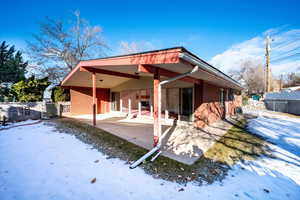 Snow covered property featuring a patio and cooling unit