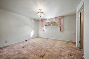 Carpeted empty room featuring an inviting chandelier