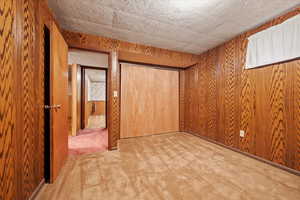 Unfurnished bedroom featuring carpet flooring and wood walls