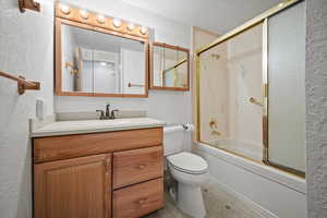 Full bathroom with vanity, toilet, and shower / bath combination with glass door