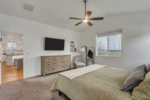 Bedroom featuring light colored carpet, vaulted ceiling, and ceiling fan