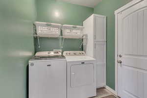 Laundry area featuring cabinets, light tile patterned floors, and washer and dryer