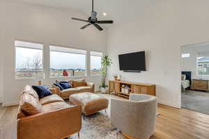 Living room with ceiling fan, light wood-type flooring, and high vaulted ceiling