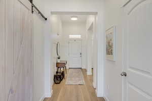 Corridor featuring a barn door and light hardwood / wood-style floors