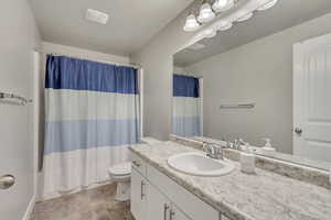 Full bathroom with shower / bath combination with curtain, vanity, and toilet