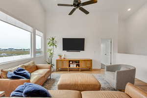 Living room featuring ceiling fan, a towering ceiling, and light hardwood / wood-style floors