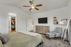 Carpeted bedroom featuring ceiling fan, a closet, a spacious closet, and vaulted ceiling