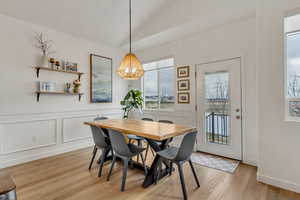 Dining space featuring light hardwood / wood-style floors, lofted ceiling, and an inviting chandelier